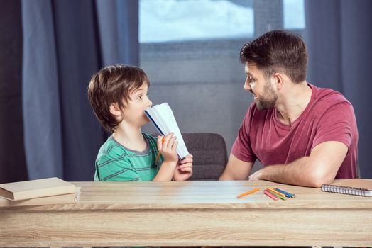 son showing done homework to father at home