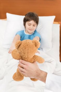 doctor showing child patient in bed teddy bear