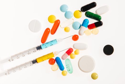 Top view of colorful medical pills and syringes on white, medicine and healthcare concept  