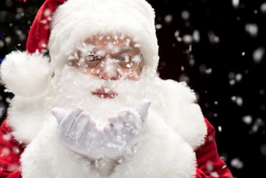 Portrait of Santa Claus blowing snowflakes from hands, Christmas coming 