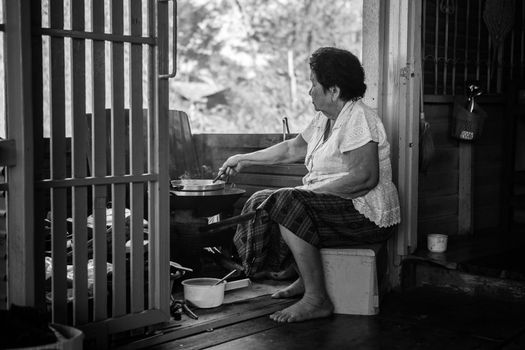 Black and white image of Senior asian woman cooking in kitchen