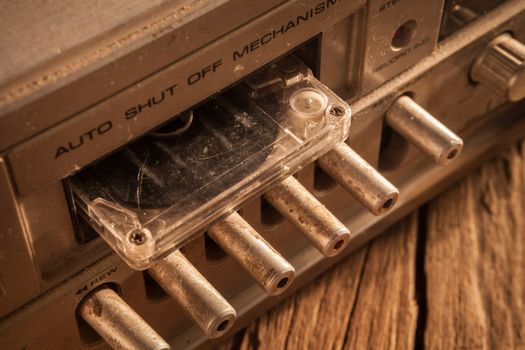 Old cassette tapes and cassette player on wooden surface