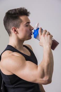 Muscular young male bodybuilder holding shaker
