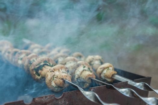 Grilled mushrooms on skewers cooked in a brazier, close-up, retr
