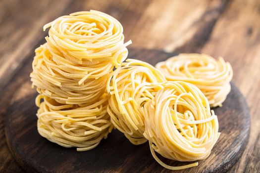 Raw all'uovo pasta, egg noodles on dark wooden rustic background, traditional italian cuisine