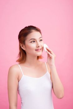 Young lady applying blusher on her face with powder puff, skin c