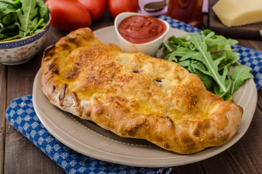Calzone pizza stuffed with cheese and prosciutto