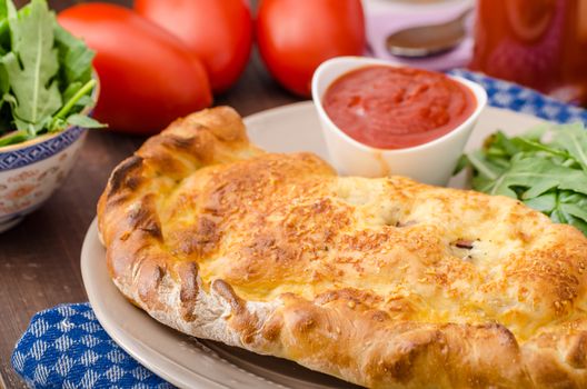 Calzone pizza stuffed with cheese and prosciutto