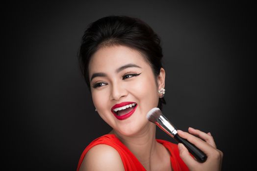 Cosmetic powder brush. Asian woman applying blusher on her cheek
