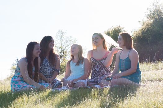 Girls Sitting Together in Grassy Field With Sunlight Overhead