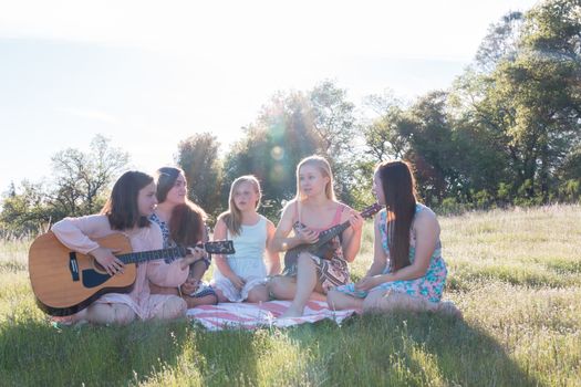Girls Sitting Together in Grassy Field Singing and Playing Music