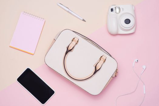 Flat lay of female fashion accessories and white handbag on past
