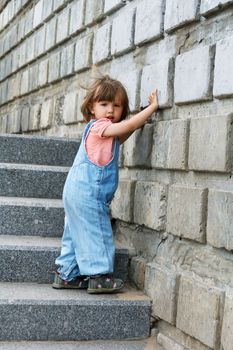 Baby girl in blue clother goes down on the stairs