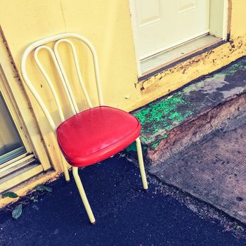 Bright chair outside the house. Old building exterior.