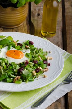 Fresh salad with nuts, raisins and fried egg