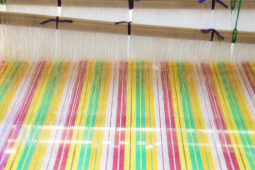 Yarn background, old weaving Loom and thread of yarn. A traditional hand-weaving loom being used to make cloth at home.Background surface blurred.