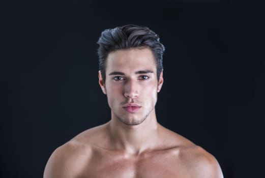 Handsome, fit topless young man isolated on black