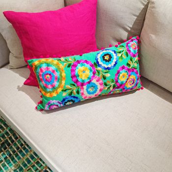 Bright pink and green cushions with floral design decorating a sofa.