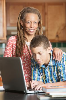 Single mother and her teen son work on computer