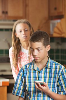 Mother looks questioningly as her teen son checks his phone