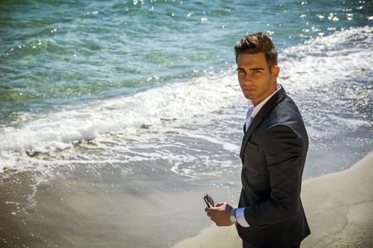 Handsome man in classical suit on beach