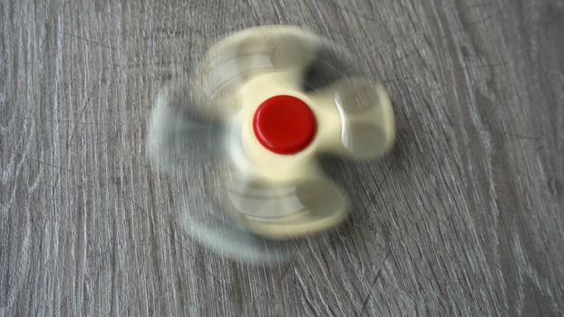 two white hand spinner spinning on grey background or fidget spinners