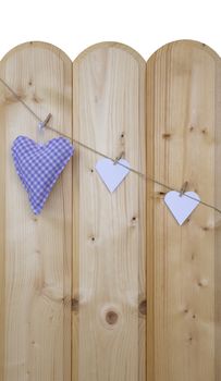 Three hearts with clothes pegs on a cord on wood