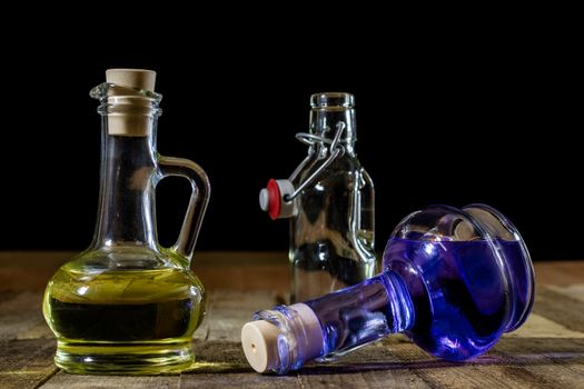 Bottles of colored liquid on a wooden kitchen table. Wooden table. Black background