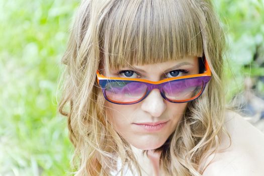 Portrait of beautiful girl with with sunglasses on green background