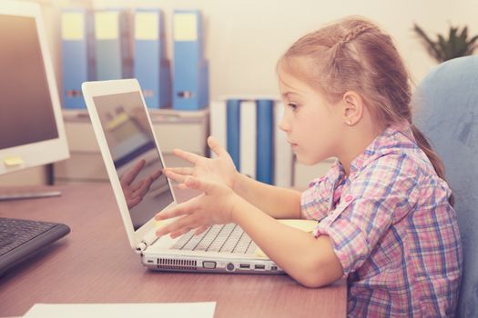 Little girl doing homework on the laptop