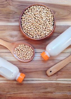 Soy milk in bottle and soy beans with wooden ladle on wooden bac