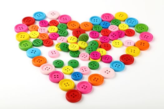 Heart shaped of colorful sewing buttons on white