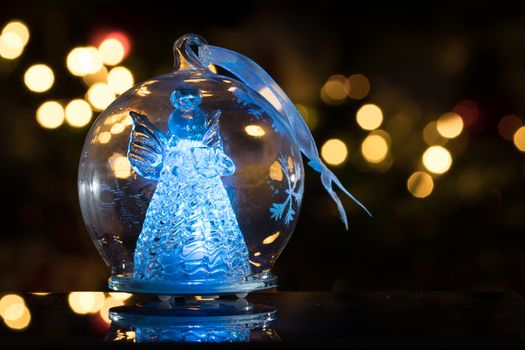 Illuminated angel figure in glass bulb, soft boke christmas ligh