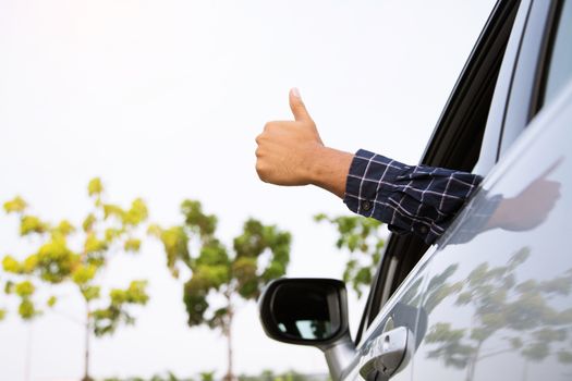 Man traveler ready to leave drive a car on the road. showing hand thumb up outdoor.