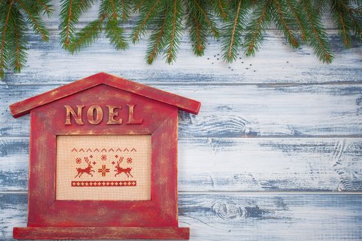 Noel house shaped frame with branches of Christmas-tree on old wooden background