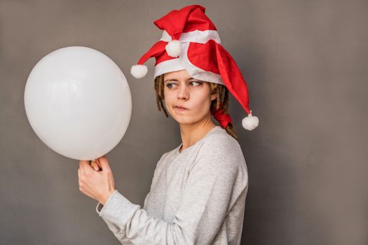 christmas young woman holding a balloon watching with doubt