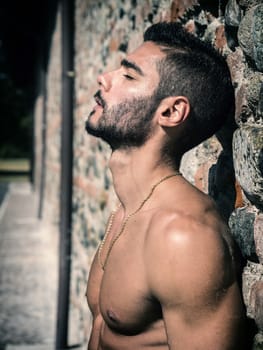 Shirtless young man outdoor against brick wall