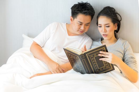 Couple reding book in bed