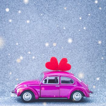 Ultraviolet toy car carries love red heart on the roof. Wedding or Valentine Day postcard invitation concept