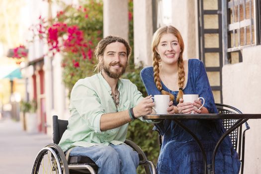 Woman with Man in Wheelchair Holding Coffee Cups
