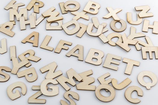 The word alphabet in Dutch translation in wooden letters diagonally placed with loose wooden letters around it.
