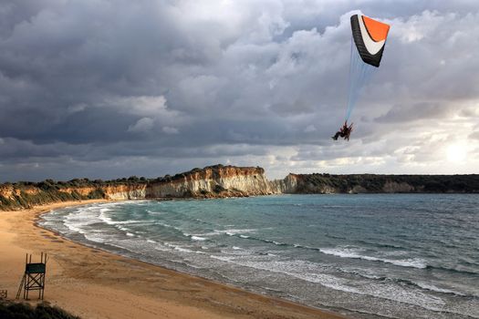 paraglider flying above a beach