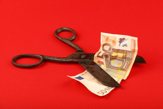 Scissors cut Euro banknote over red background