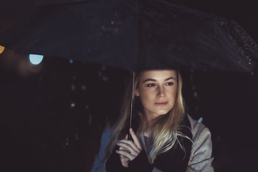 Thoughtful woman outdoors on rainy night
