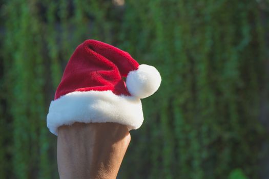 Hand of woman with Santa Claus red hat in Christmas day on natur