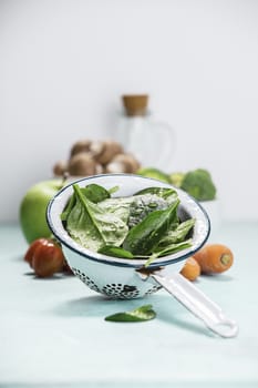 Fresh organic spinach leaves in metal colander and healthy ingre