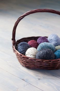 Colorful balls of wool yarn in a basket on the rustic background
