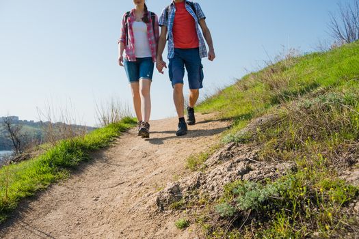 Young Couple Hiking with Backpacks on the Beautiful Rocky Trail at Sunny Evening. Family Travel and Adventure.
