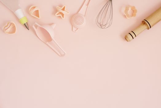 Cookie cutters and kitchen bake tools for making sweets. Pastel pink background. Top view of a holiday baking still life