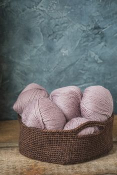 Knitting pink wool yarn in the crocheted basket